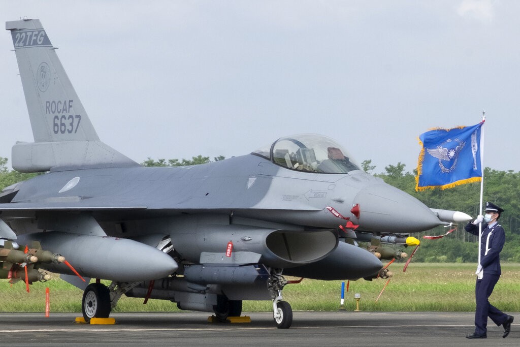 A Taiwanese Air Force flag bearer passes by one of the newly commissioned upgraded F-16V fighter jets at Air Force base in Chiayi in southwestern Taiw...