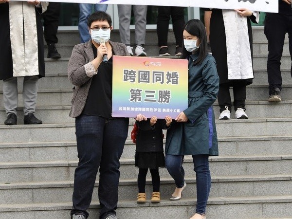 Mei Ping, daughter, Xiao C hold sign which reads, "Transnational same-sex marriages third victory." 
