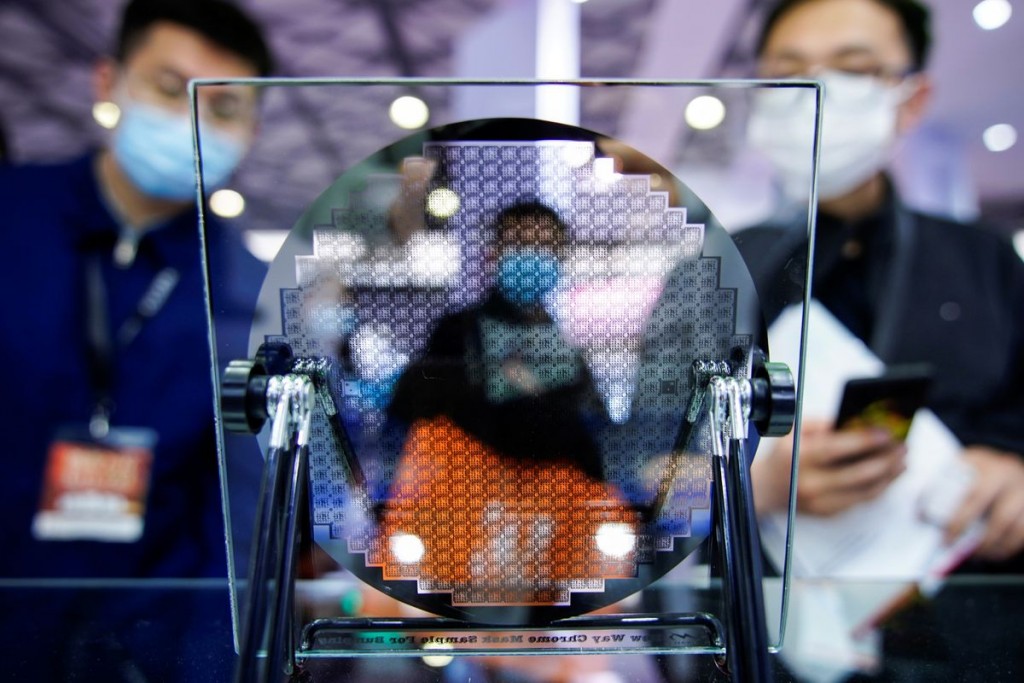 Visitors look at a display of a semiconductor device at Semicon China, a trade fair for semiconductor technology, in Shanghai, China March 17, 2021. R...