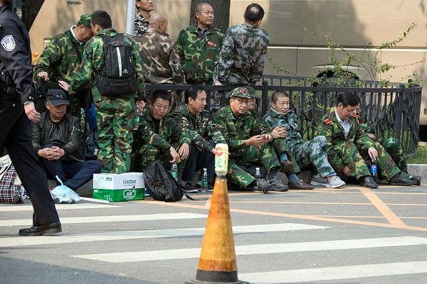 A bunch of Chinese veterans sit on a roadside in Beijing in 2016.

