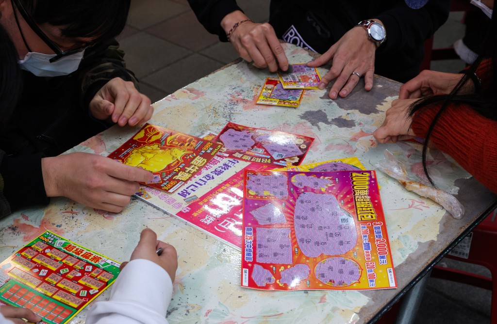 A group of people playing scratch card lotteries. 
