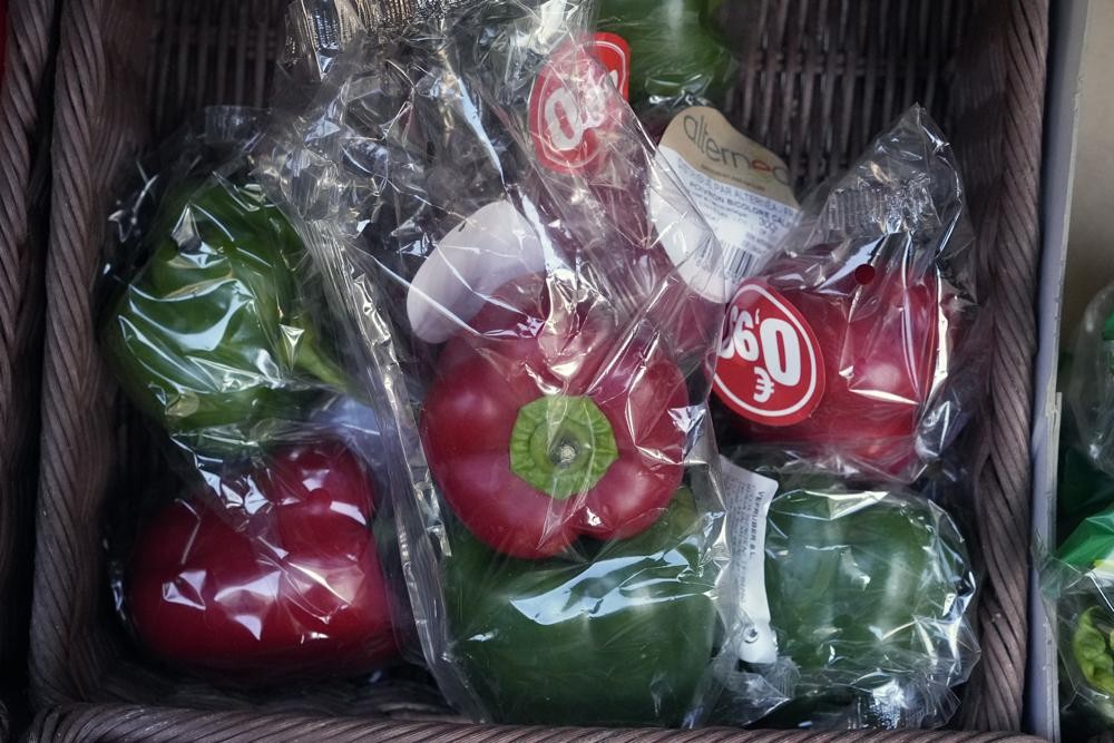 Vegetables wrapped in plastic at a French grocery stall.
