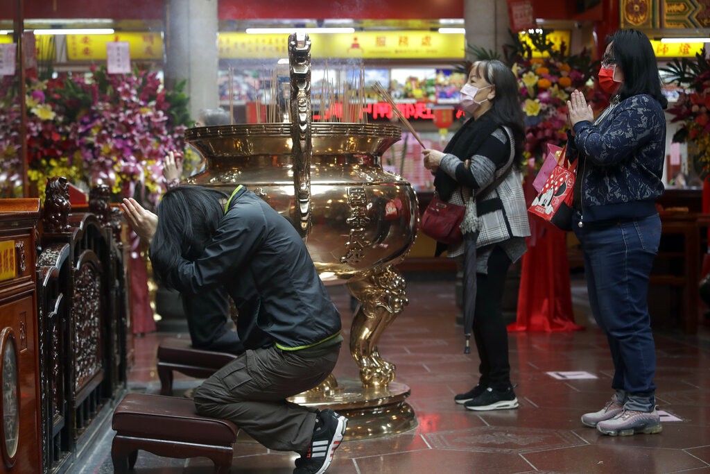 People wear face masks to protect against the spread of the coronavirus and pray at a temple in Taipei, Taiwan, Dec. 28, 2021.
