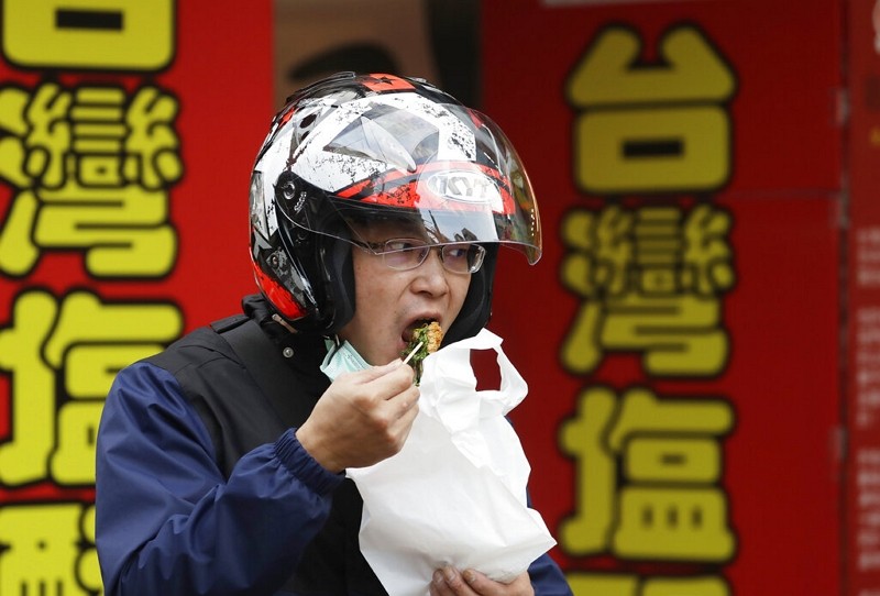 A man takes his protective mask off to eat as epidemic prevention moves into phase two in Taipei, Taiwan, Wednesday, Dec. 29, 2021. 
