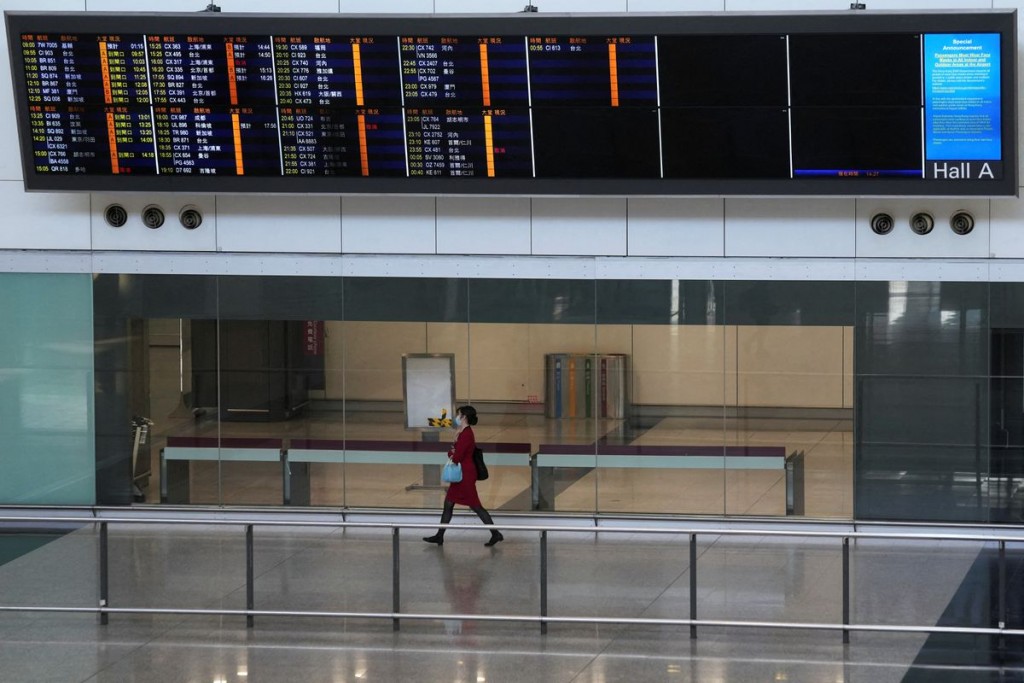 A flight attendant walks under an information board at the arrivals hall of Hong Kong International Airport, following infections of the coronavirus d...