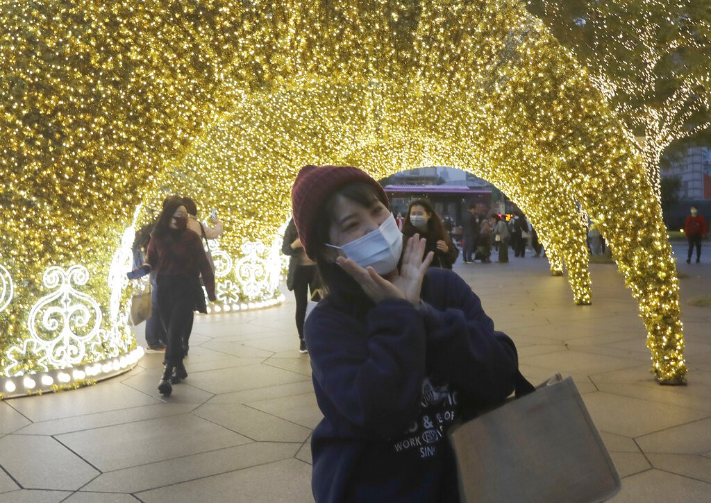 People wear face masks to protect against the spread of the coronavirus as they walk by Christmas decoration in Taipei, Taiwan, Friday, Dec. 17, 2021....