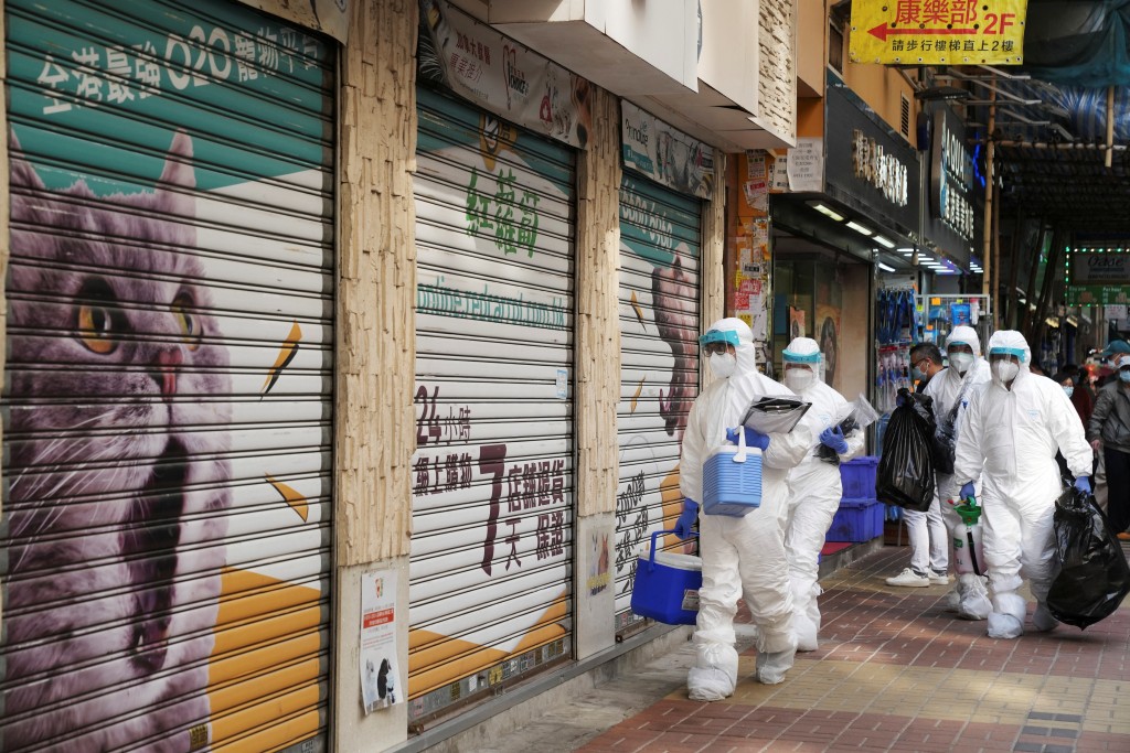 Officers in protective suits walk outside a closed pet shop in Mong Kok district after a hamster cull was ordered to curb the coronavirus di...