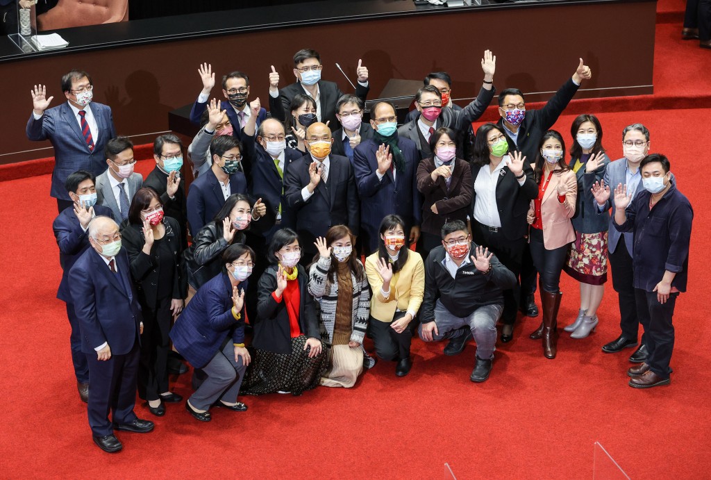 Premier Su Tseng-chang (with orange mask, center) congratulates lawmakers on passing the 2022 central government budget. 
