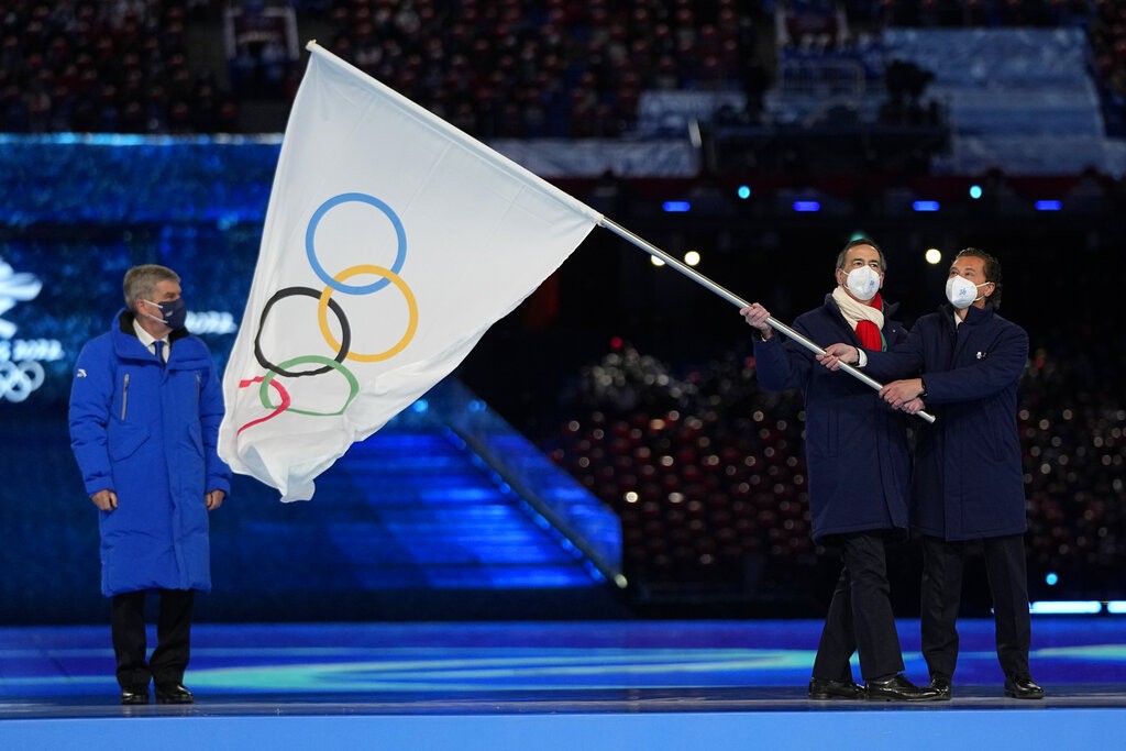 冬奧閉幕式上，國際奧委會主席巴赫將會旗交給下屆主辦城市義大利米蘭市長薩拉和柯蒂納戴比索市長格迪那。 （圖／美聯社）
