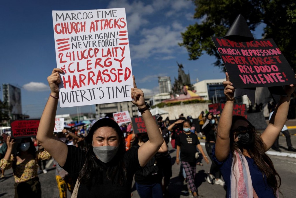 Filipinos raise their fists and placards during a rally marking the anniversary of the 1986's People Power Revolution that overthrew the late dict...