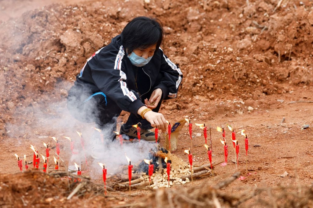A woman surnamed Liang, 60, takes part in a Buddhist ceremony in honor of the victims in a field close to the entrance of Simen village, near the site...