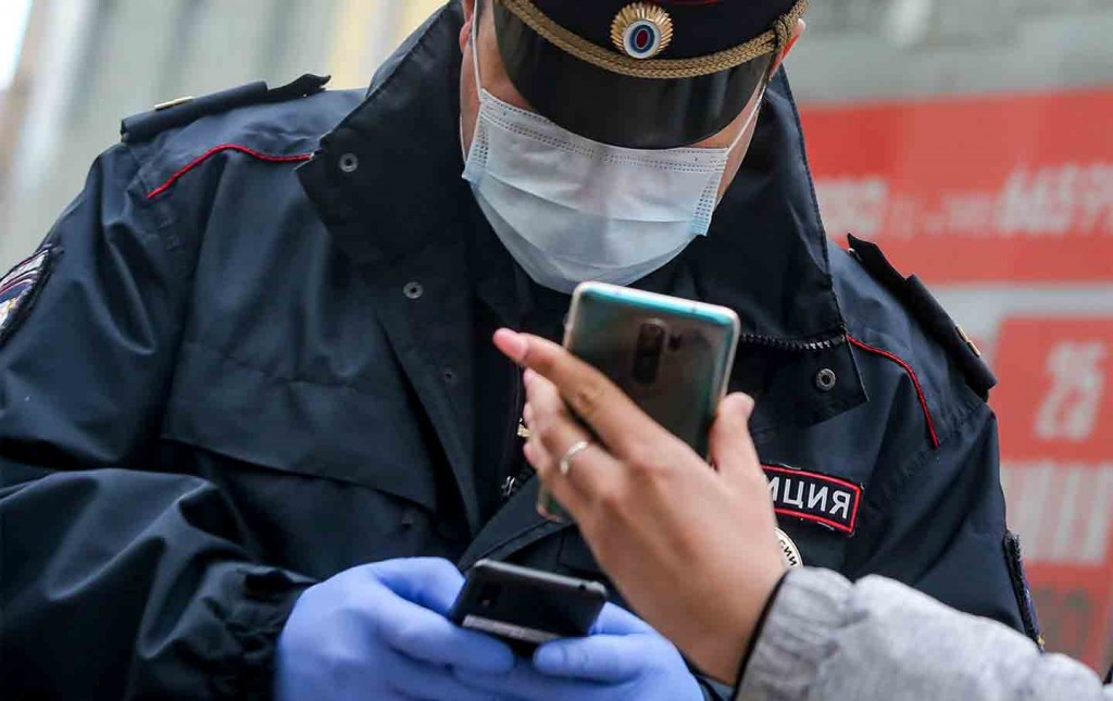 A Russian police officer checks a QR code on a woman's smartphone in Moscow. 
