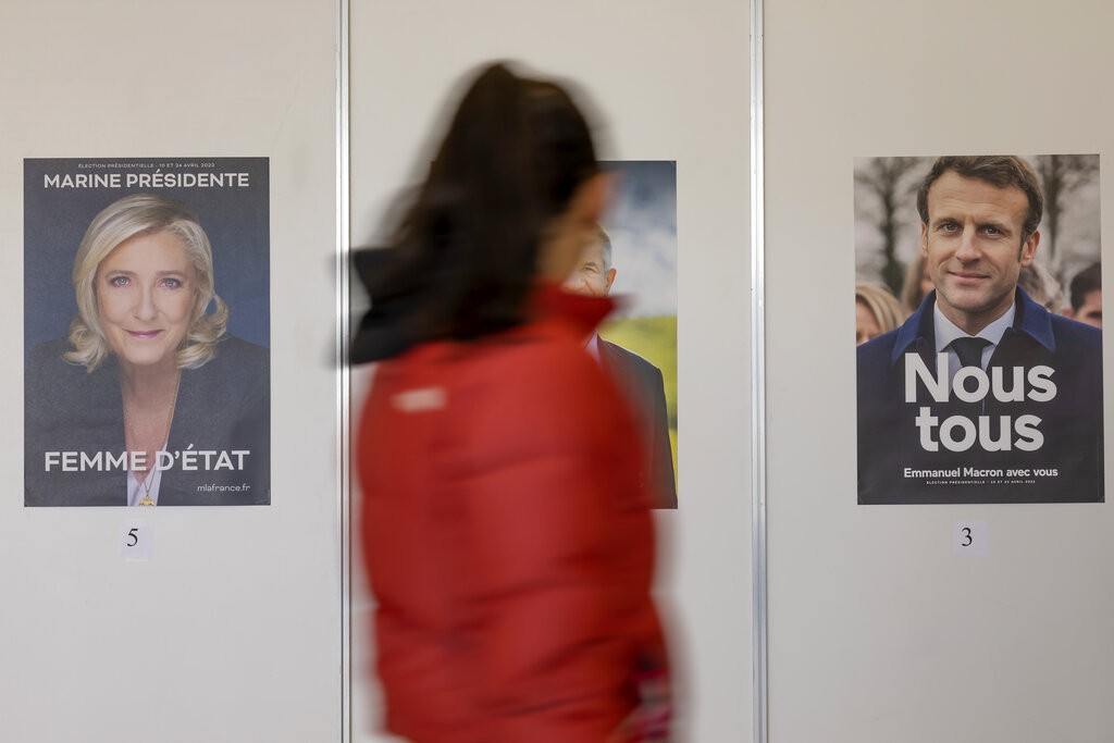 A voter walks past election poster of Marine Le Pen and of Manuel Macron for the going voting for the French presidential election at the Palexpo poll...