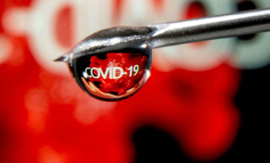 The word "COVID-19" is reflected in a drop on a syringe needle in this illustration taken November 9, 2020. REUTERS/Dado Ruvic/File Photo
