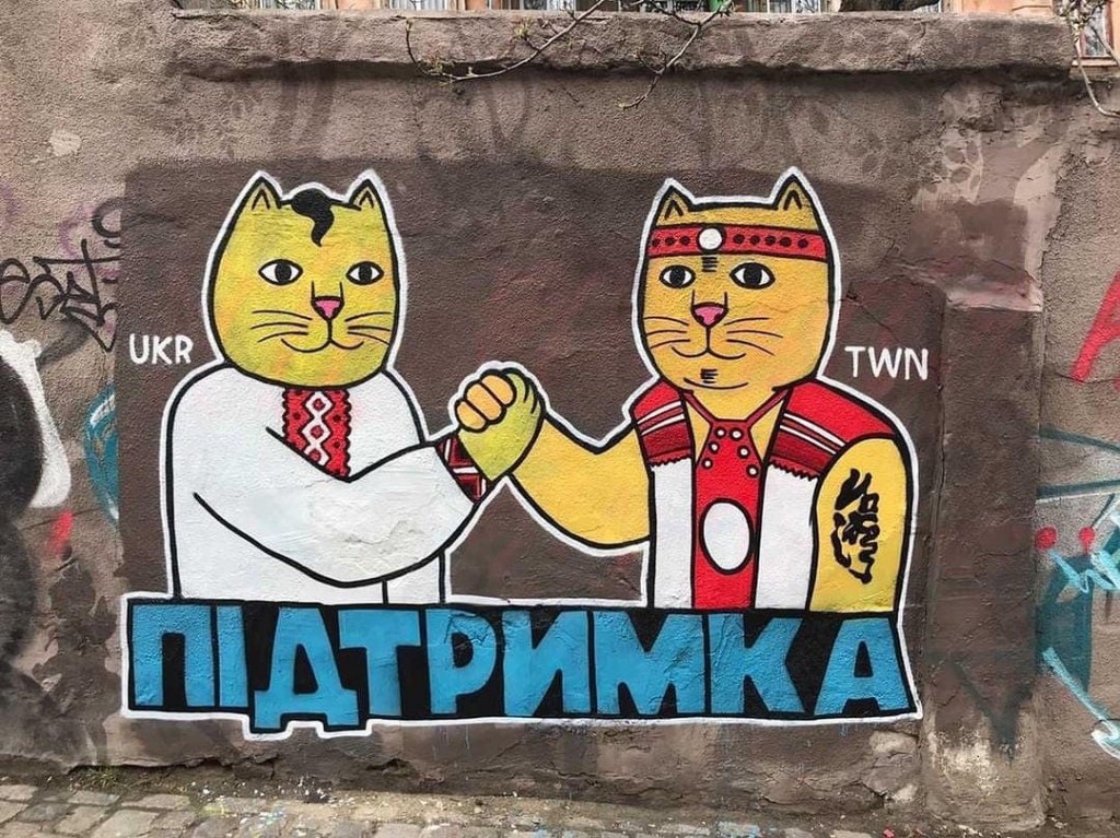 Cats wearing Ukrainian and Taiwanese Indigenous garb shake paws. (Instagram LBWS Cat Ukraine photo)
