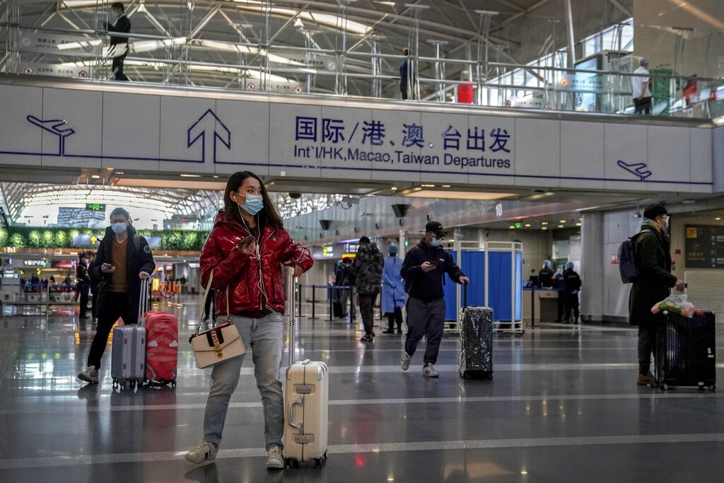 Passengers wearing face masks to help curb the spread of the coronavirus arrive at the departure hall of the Beijing Capital International Airport to ...