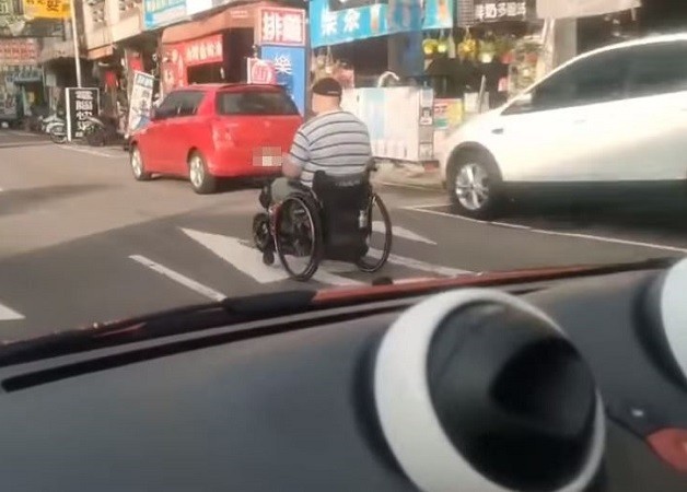 Man seen rapidly rolling by on electric wheelchair. (Facebook, Baofei Commune screenshot)
