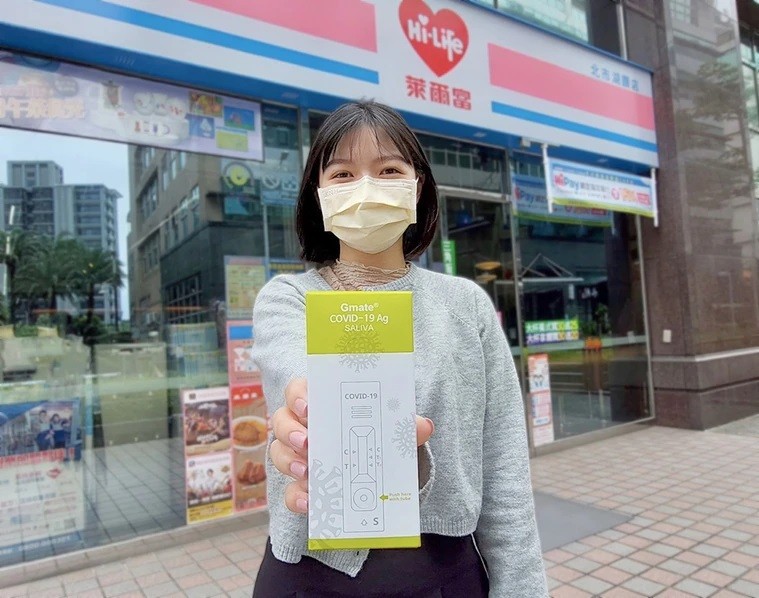 Woman holds Gmat COVID-19 saliva rapid test kit in front of Hi-Life store. (Hi-Life photo)
