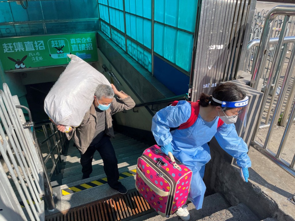 Travellers carrying luggages leave a subway station on the first day of parts of city's subway services resumed, following the coronavirus disease...