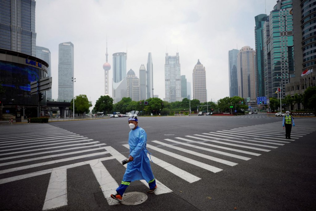 A worker in a protective suit walks on a pedestrian crossing at an intersection in Lujiazui financial district, after the lockdown placed to curb the ...
