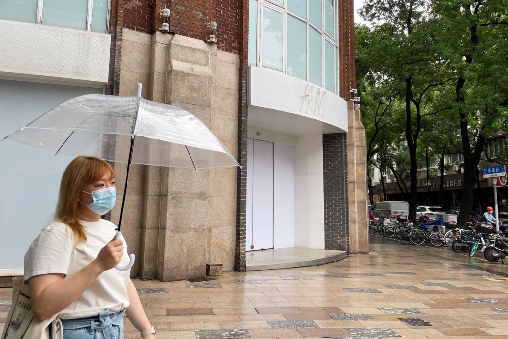 A woman, wearing a mask, amid the coronavirus disease (COVID-19) pandemic, walks past a closed flagship store of Swedish fashion retailer H&M in S...
