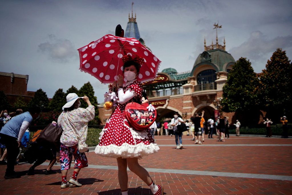  

A visitor wearing a face mask poses at the Shanghai Disney Resort, as the Shanghai Disneyland theme park reopens after being shut for the coro...