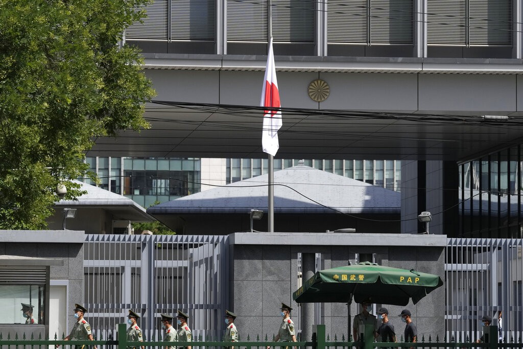 圖為日本前首相安倍遇刺身亡隔天7月9日, 一群中國武警, 路過降半旗的日本駐北京大使館 (美聯社) 
