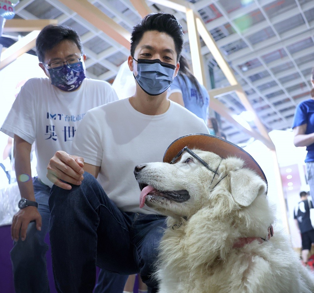 國民黨台北市長參選人蔣萬安（右）10日到南港展覽館參觀台北寵物用品展，並與參展民眾的愛犬互動。中央社
