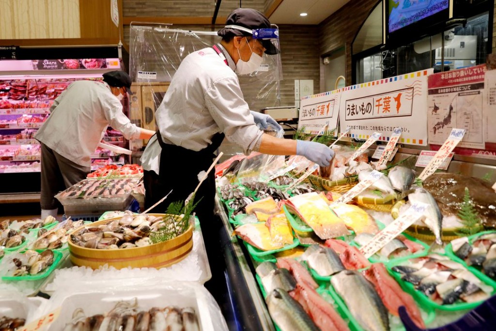 A staff wearing a face shield sells fish at Japan's supermarket group Aeon's shopping mall as the mall reopens amid the coronavirus disease (C...