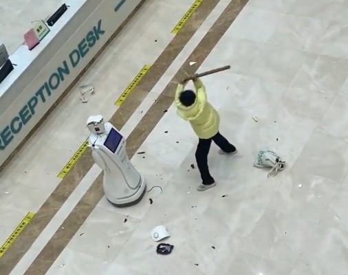 Woman hits robot with club. (Weibo screenshot)
