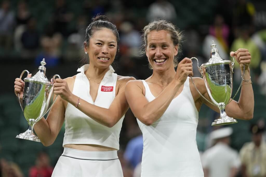 Hsieh Su-wei (left) and Barbora Strycova celebrate winning Wimbledon doubles title by holding up trophies. 
