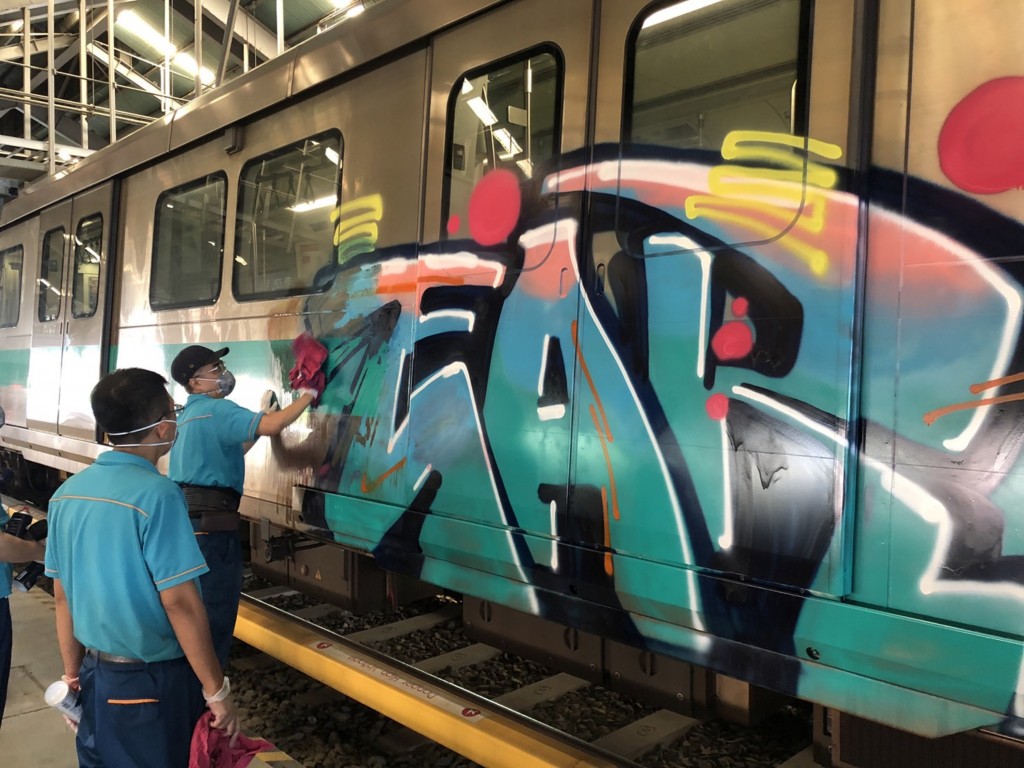 Workers remove graffiti from an MRT train in Kaohsiung Friday. (CNA, Kaohsiung MRT photo)

