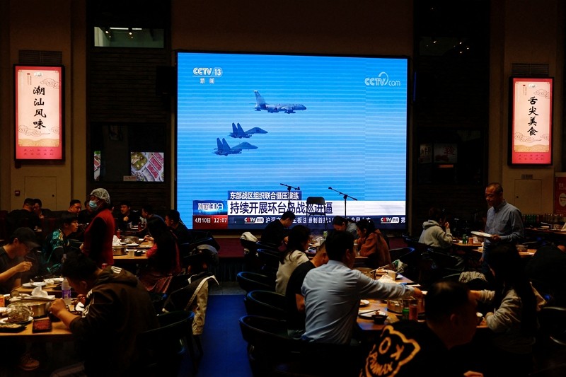Customers dine near a giant screen broadcasting news footage of aircraft of the Air Force under the Eastern Theatre Command of China's People...