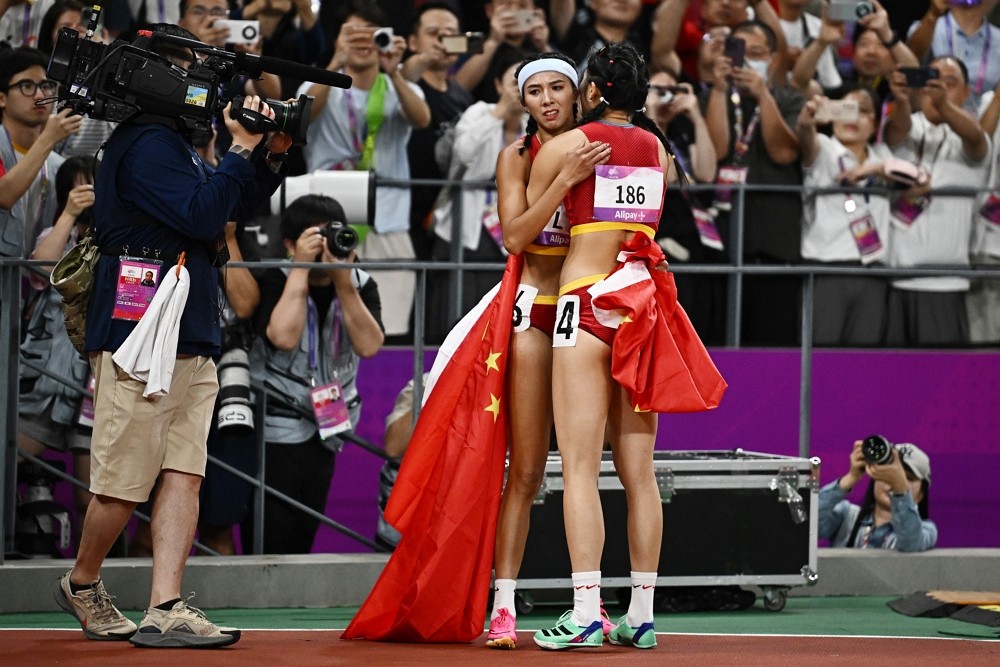 杭州亞運女子百尺跨欄決賽，中國田徑選手6號林雨薇擁抱4號吳豔妮（圖／路透社Dylan Martinez）
