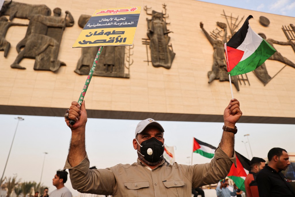 A man holds a placard and a flag, as Iraqis gather during a protest in solidarity with Palestinians in Gaza, in Baghdad, Iraq, October 7, 2023. REUTER...