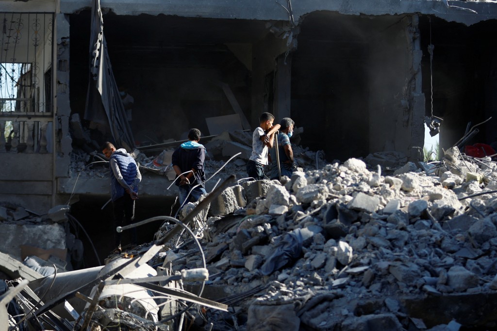 在遭到以色列攻擊後，巴勒斯坦人在加薩地區南部的一處廢墟下找尋傷亡者（圖／路透社IBRAHEEM ABU MUSTAFA）
