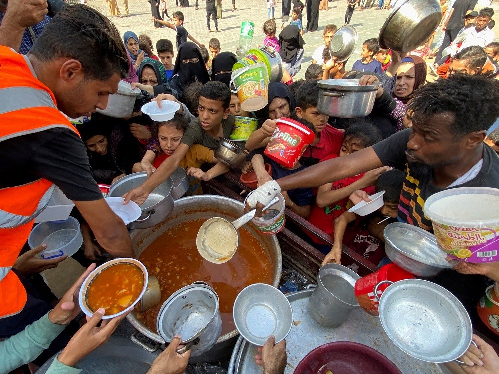 巴勒斯坦人民在糧食短缺情況下，於聯合國開辦的一所位於加薩南部的學校避難，圖中人民正向志工領取食物（圖／路透社Mahmoud al-Masr...
