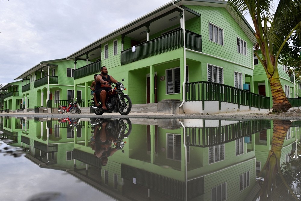 A man riding a motorbike is seen reflected in a puddle of water in Funafuti, Tuvalu, August 13, 2019. AAP Image/Mick Tsikasvia via REUTERS
