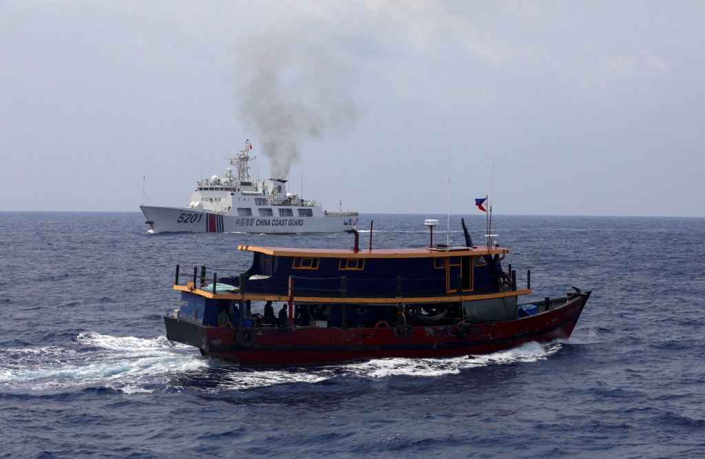 A Philippine supply boat sails near a Chinese Coast Guard ship during a resupply mission for Filipino troops stationed at a grounded warship in the&nb...