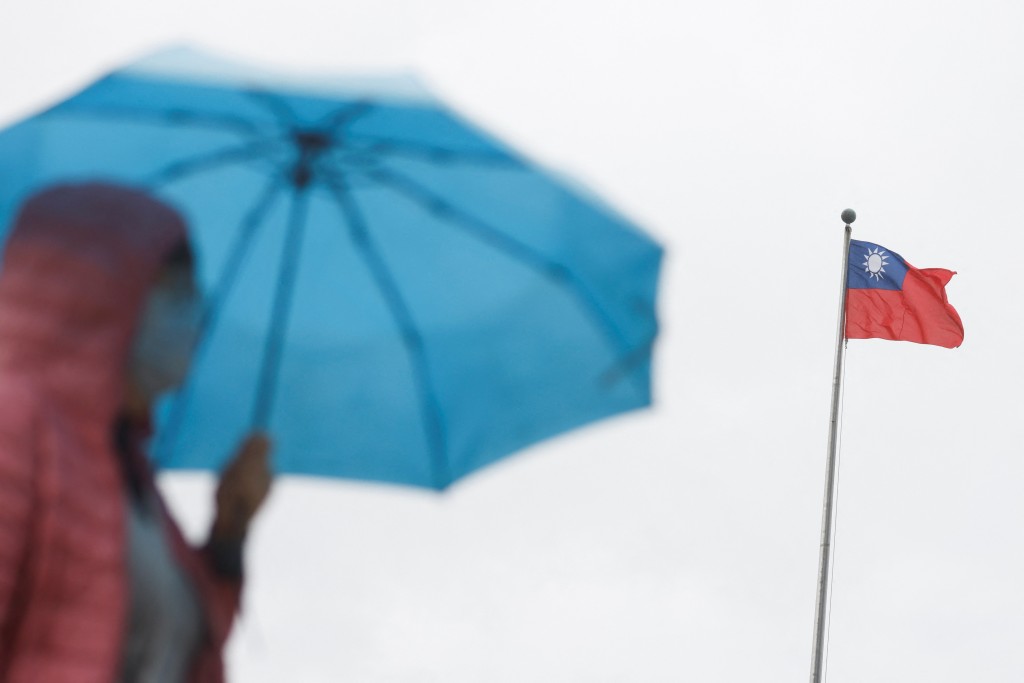 A woman holding an umbrella walks near a Taiwanese flag outside the Sun Yat-Sen Memorial Hall in Taipei on Thursday. (Reuters, Carlos Garcia Rawlins p...