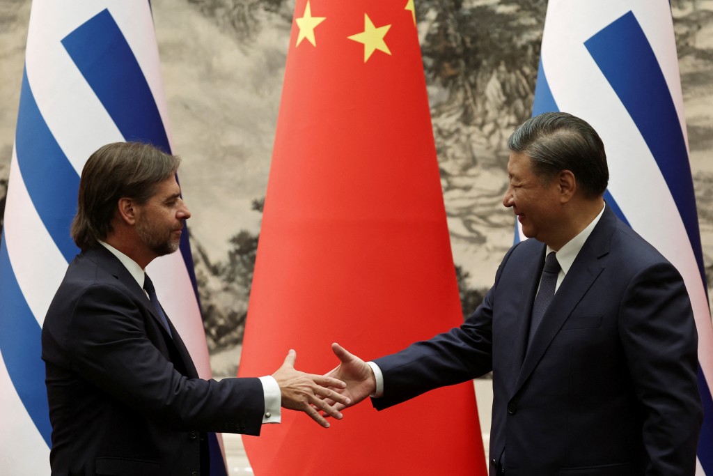 Chinese President Xi Jinping and Uruguayan President Luis Lacalle Pou reach to shake hands during a signing ce...