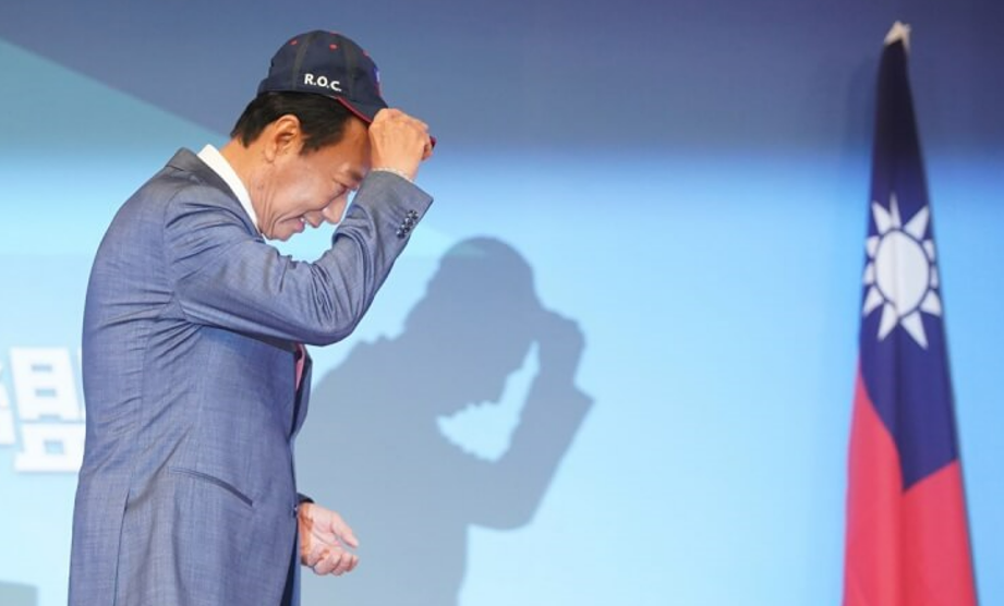 Terry Gou tips hat and bows at Taiwan flag. 
