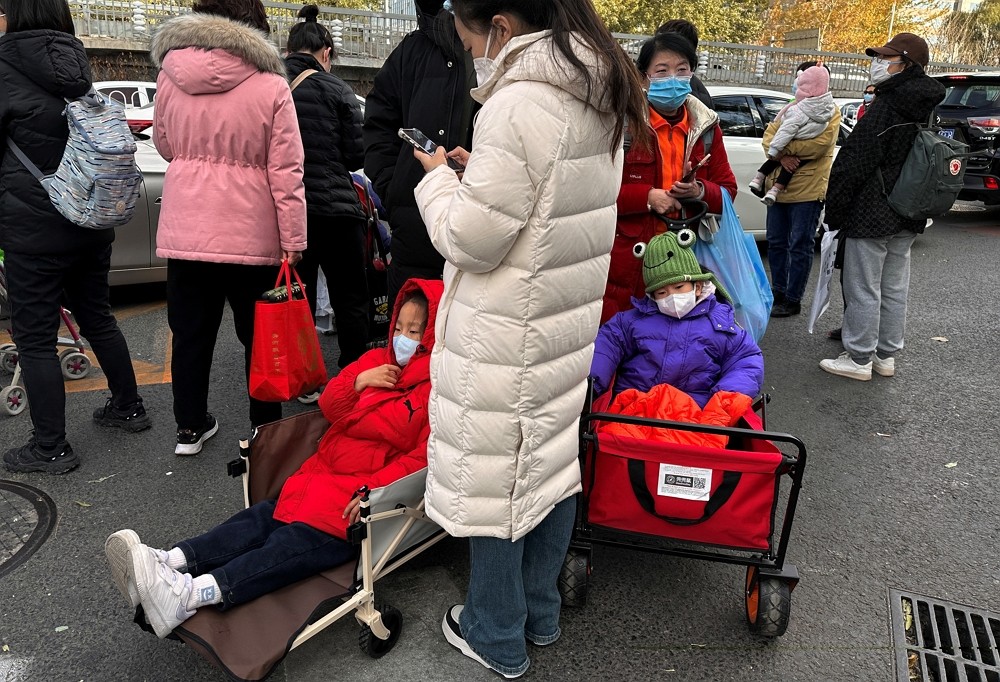 People stand next to children sitting in camping carts as they wait for their rides outside a children's hospital in Beijing, China...