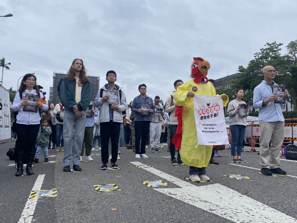 Animal rights activists illustrate the fate of battery hens by standing on an A4 page in Taipei Saturday. 
