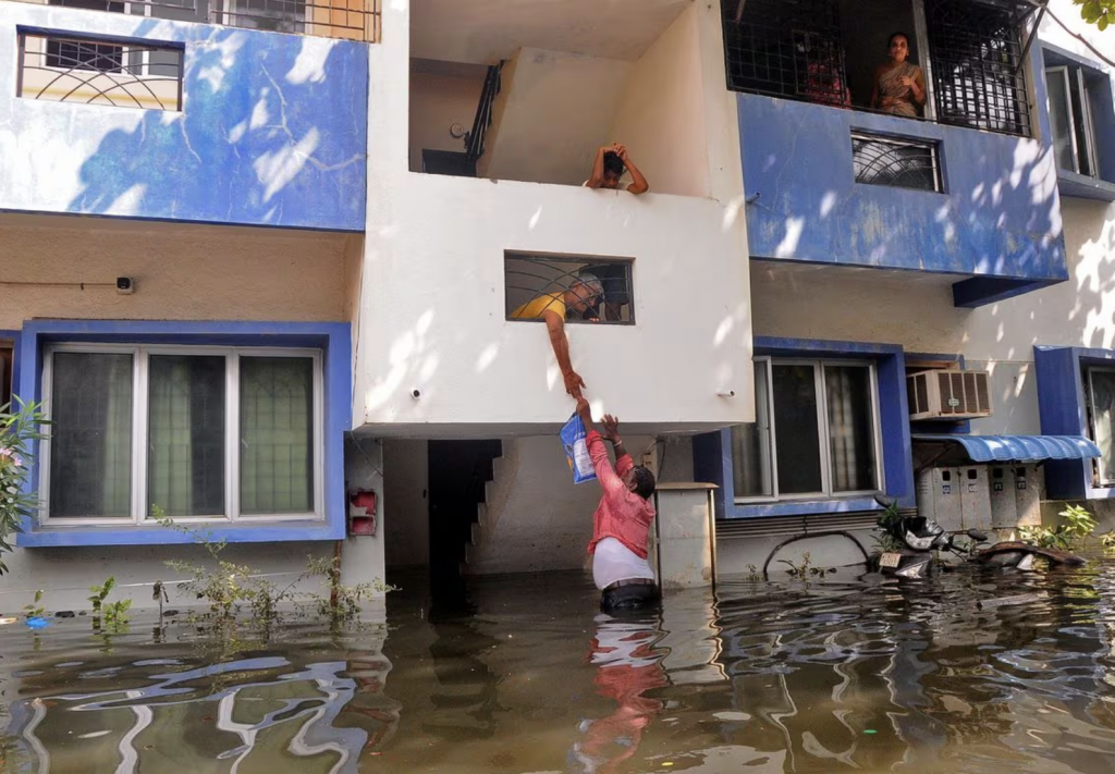 A volunteer offers food to a resident after his house got partially submerged following heavy rains due to Cyclone Michaung, in Chennai, India, Decemb...