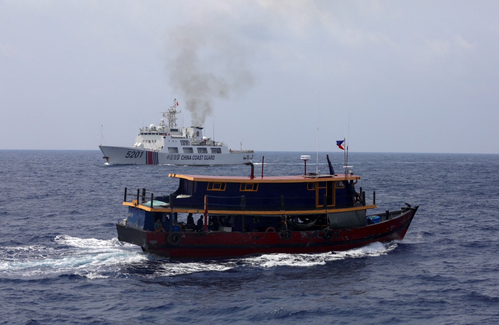 圖為菲律賓一補給船在南海一處執行運補任務予駐在南海一島上的菲律賓軍隊後返程畫面，此時一艘中國海巡船在附近監視。（圖片／路透社)
