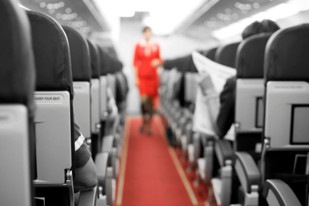 A flight attendant is pictured walking between seats in an airplane in this stock image. (Canva image)
